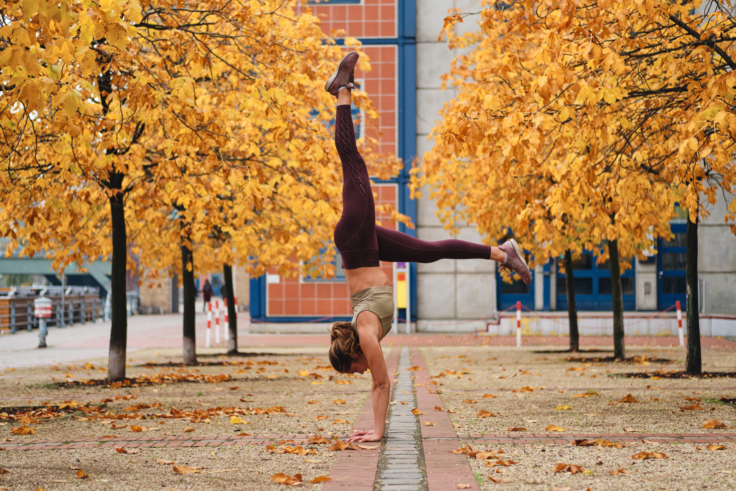 standing on hands during yoga practice on autumn street